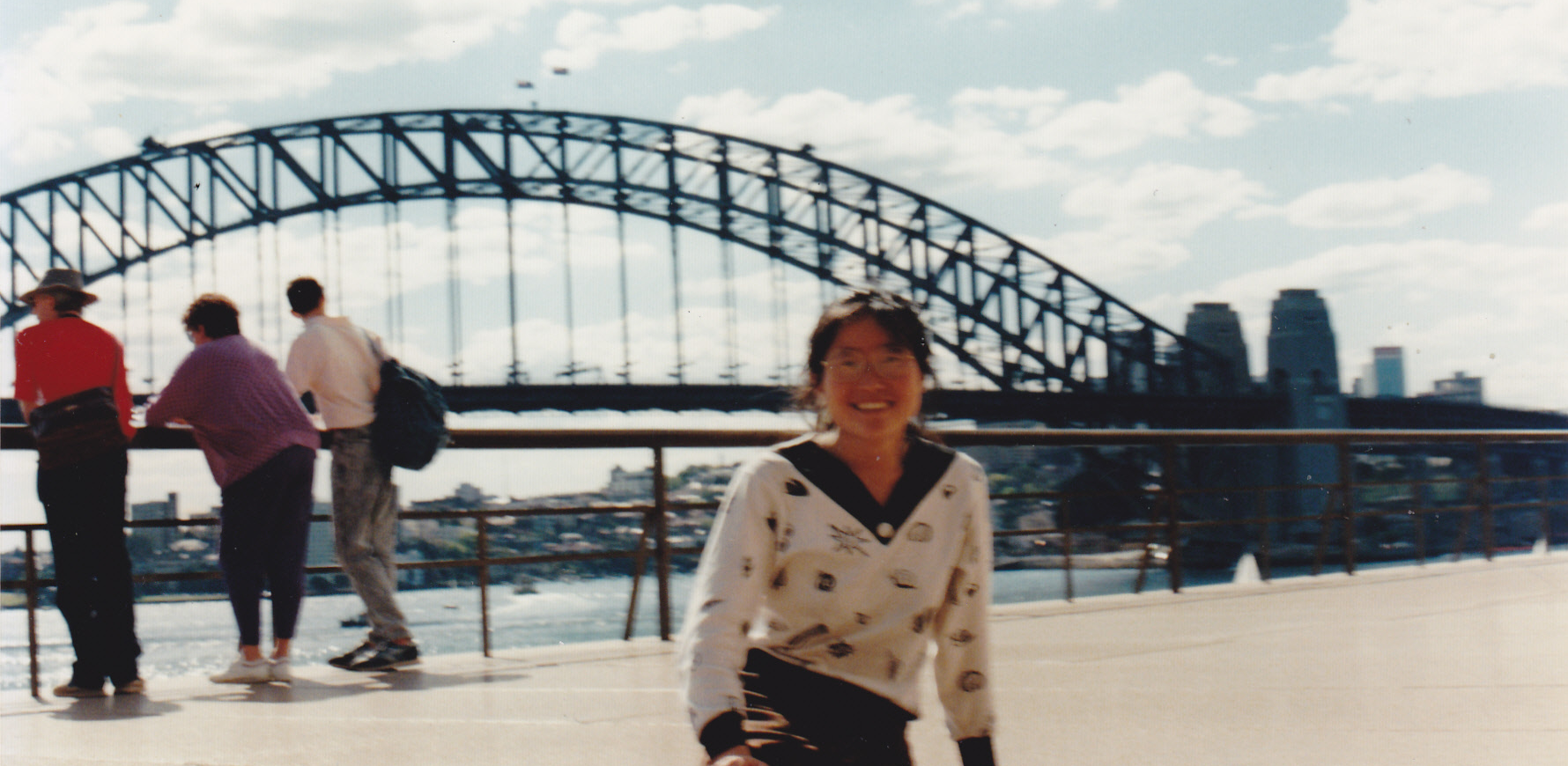 woman sitting posing in front of sydney harbor bridge