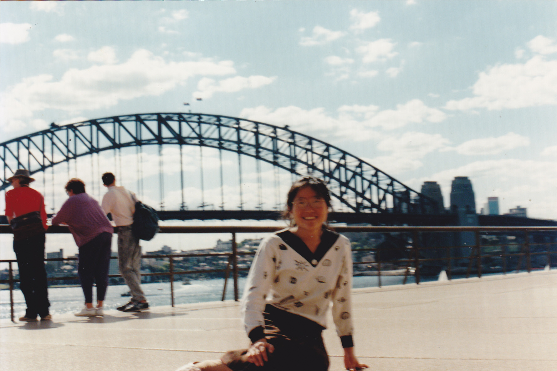 retro picture of mom sitting on grass in front of the sydney harbor bridge